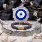 Bracelet with evil eye design on a round stone surface with dried flowers.